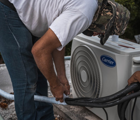 professional in white shirt and camouflage hat working on HVAC unit